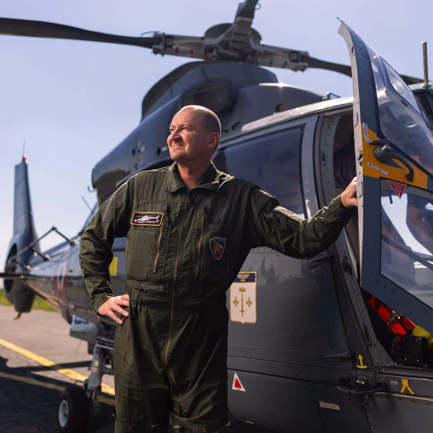 Pilote hélicoptère devant un appareil en uniforme de vol